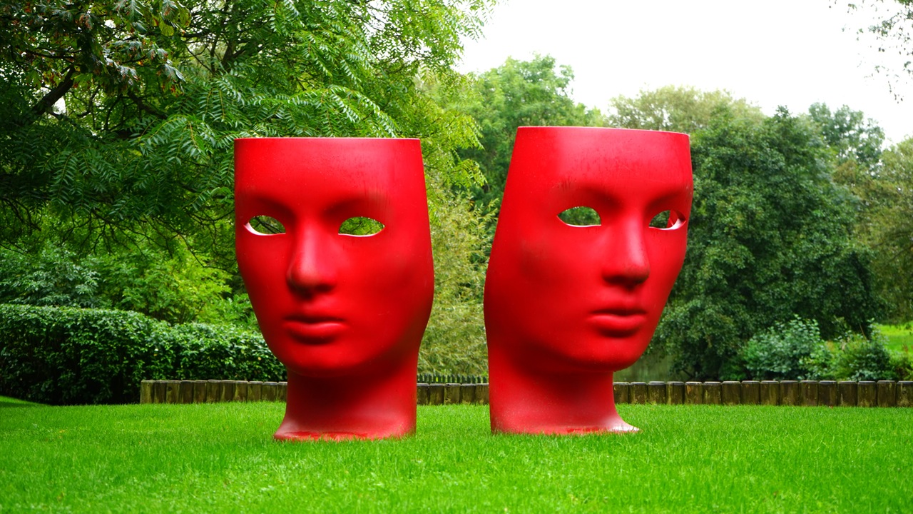 Sculpture of red theater masks on green grass